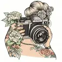 woman with hair up in a messy bun holding camera taking a picture. her shit in hanging down her left shoulder. floral tattoo design idea