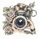 woman with hair up in a messy bun holding camera taking a picture. her shit in hanging down her left shoulder. floral tattoo design idea